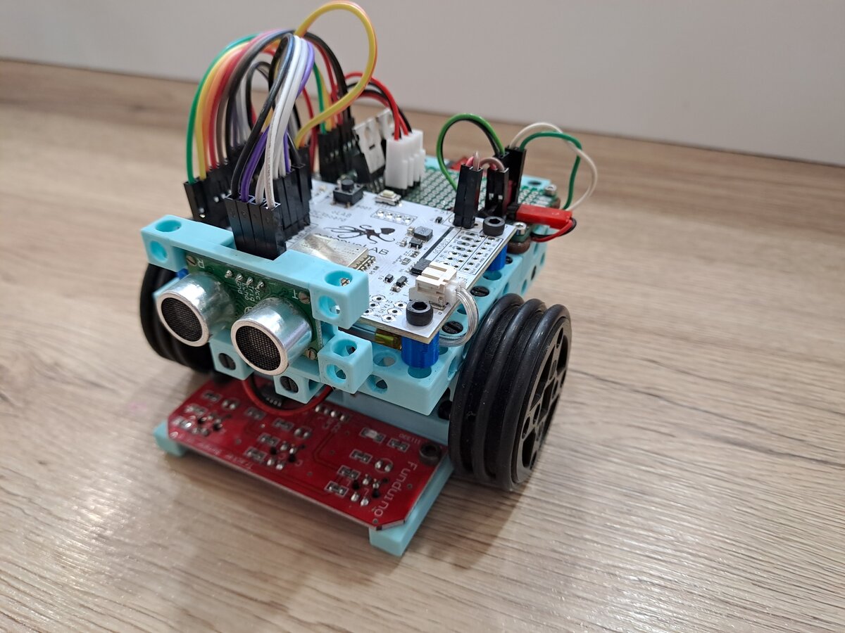 Fotografie robota Robina postaveného ze stavebnice BitBeam s deskou OctopusLab ESP32C3, dvěma DC motory a ultrazvukovými senzory